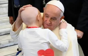 Papa Francisco abraça uma criança na Sala Paulo VI do Vaticano.