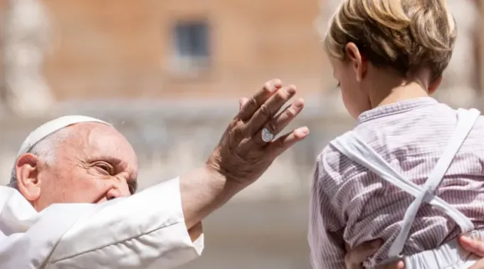 Imagem ilustrativa do papa Francisco saudando um menino durante a audiência geral