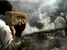 Multidão de muçulmanos joga tijolos em casa cristã depois de incendiá-la em Lahore, Paquistão, em 9 de março de 2013.