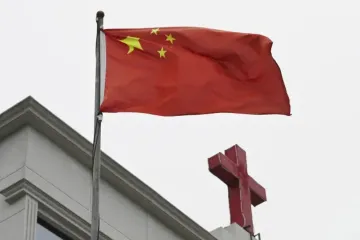 Bandeira chinesa tremula ao lado de cruz