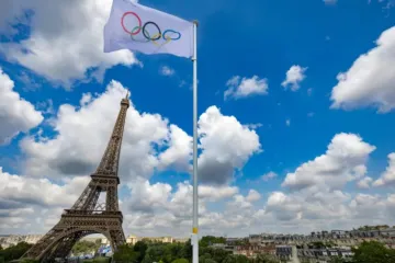 Bandeira olímpica em estádio próximo à torre Eiffel