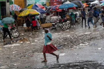 Mulher caminha na chuva no Haiti