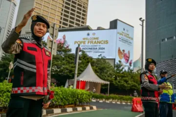 Policiais indonésios direcionam trânsito ao lado de outdoors que exibem mensagem de boas-vindas ao papa Francisco