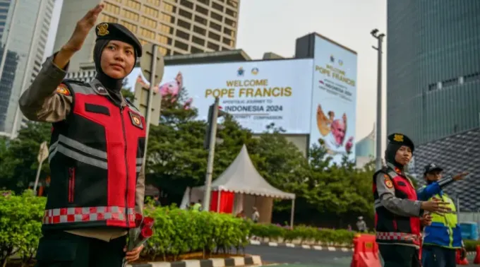 Policiais indonésios direcionam trânsito ao lado de outdoors que exibem mensagem de boas-vindas ao papa Francisco ?? 