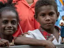 Duas crianças, uma delas segurando uma estátua do beato Pedro To Rot, aguardam no sábado (7) a visita do papa Francisco à Escola Secundária Técnica da Caritas em Port Moresby, Papua-Nova Guiné.