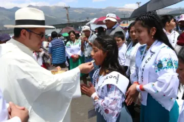 Padre dá a comunhão a crianças  no Congresso Eucarístico Internacional 2024