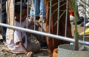 Criança sentada em papelão assiste a missa celebrada hoje (10) pelo papa Francisco em Timor-Leste. | Crédito: Daniel Ibáñez/EWTN News