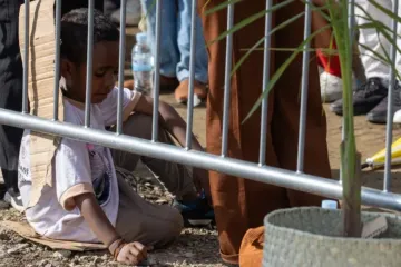 Criança sentada em papelão assiste a missa celebrada hoje pelo papa Francisco em Timor-Leste