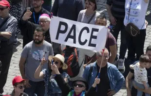 Peregrinos na praça de São Pedro, no Vaticano, com faixa que diz "Pace" ("Paz", em italiano).