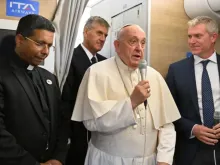 Papa Francisco fala a jornalistas a bordo do avião papal com destino à Mongólia, com o futuro cardeal George Jacob Koovakad à esquerda, em 31 de agosto de 2023.