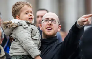 Pai participa com o seu filho da oração do Ângelus na Praça de São Pedro, no Vaticano.