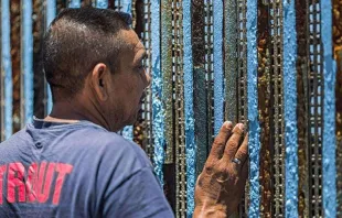 Um homem olha para o outro lado do muro fronteiriço entre o México e os Estados Unidos.