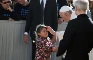 Papa abençoa uma menina na audiência.