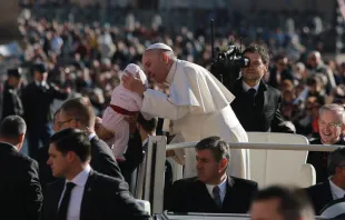 Papa Francisco beija um bebê na Praça de São Pedro.